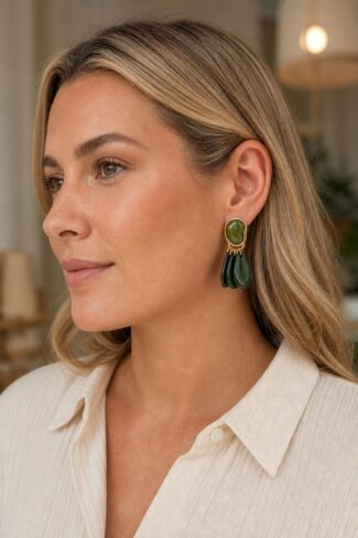 Groene oorbellen met goudkleurige details, uitgevoerd in een ovale vorm, gedragen aan het oor